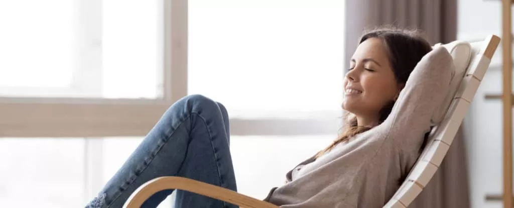 Relaxed calm young woman lounging sitting in comfortable rocking chair after Stress Management Therapy session