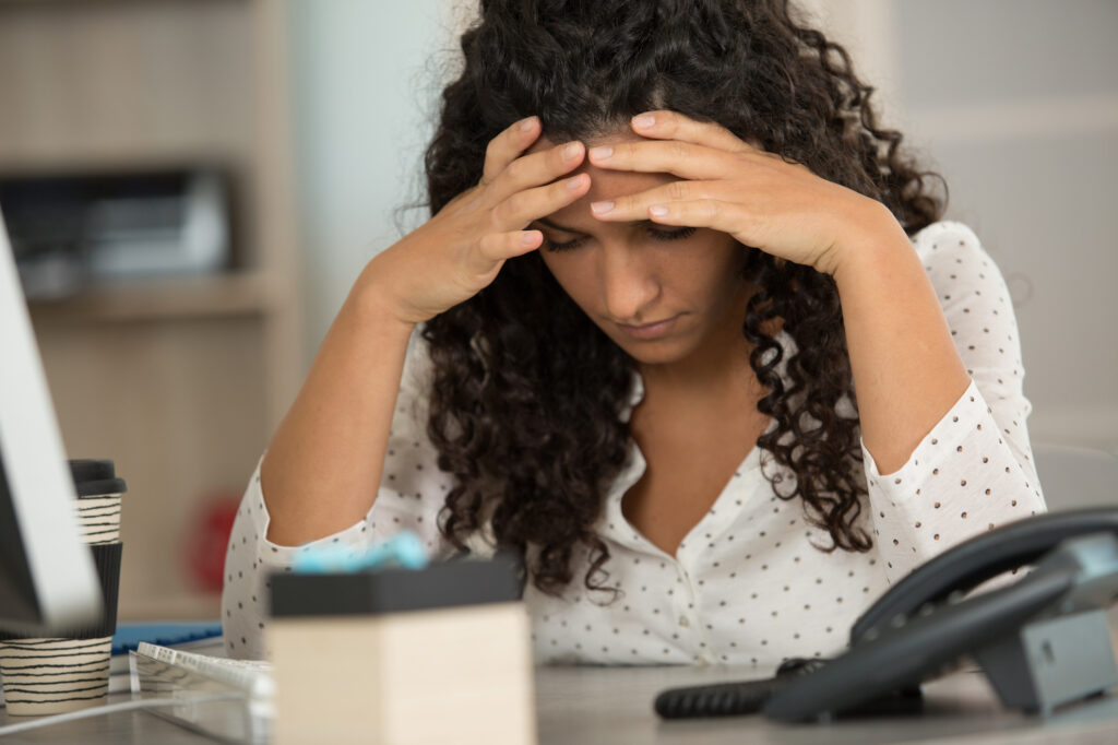 stressed young Latinx woman struggling with imposter syndrome at work