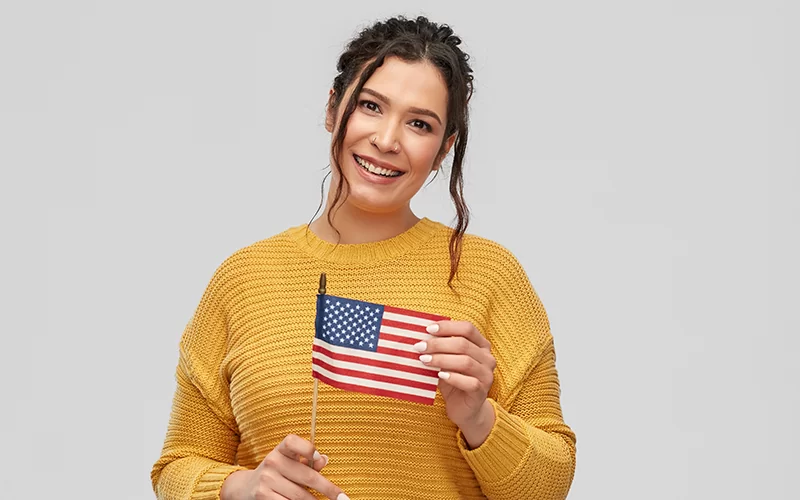Immigration Evaluations - happy smiling young woman with flag of united states