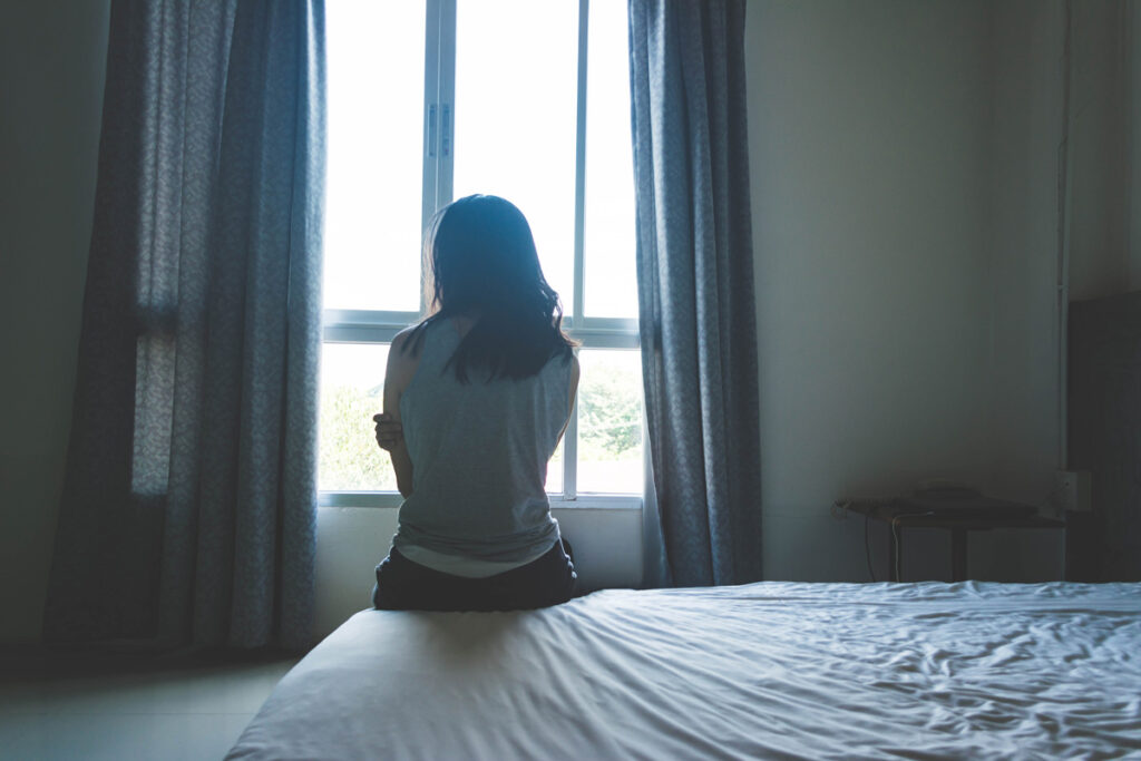 A person sitting on a bed in sadness in Chicago.