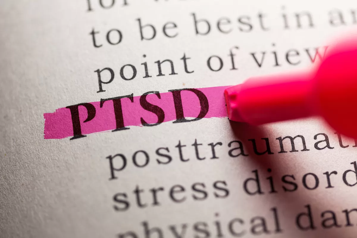 The printed letters “PTSD” on a piece of paper are highlighted by a pink marker in Chicago.